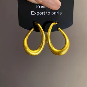 Detailaufnahme von goldenen Retro-Ohrringen in gedrehter ovaler Form mit Matt-Effekt