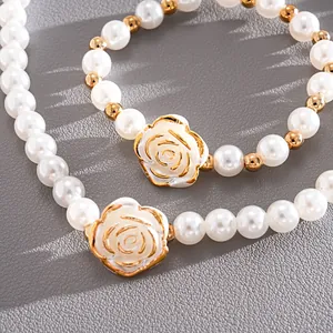 Macro view of vintage faux pearl jewelry set featuring gold-edged acrylic camellia charms