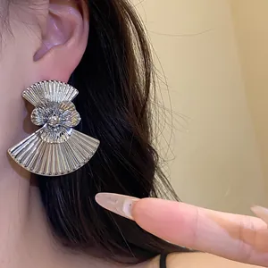 Close-up showing the intricate pleated texture of a silver fan-shaped flower earring