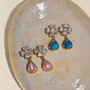 Vista dettagliata di eleganti orecchini a fiore e goccia rosa e blu su piatto ceramica