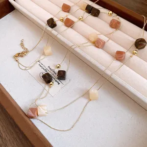 Close-up of double-layered necklace with Maillard-colored acrylic square beads in a display box.