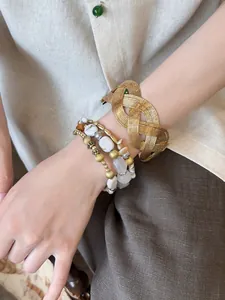 Detail shot of vintage gold woven cuff and stacked beaded bracelets on wrist