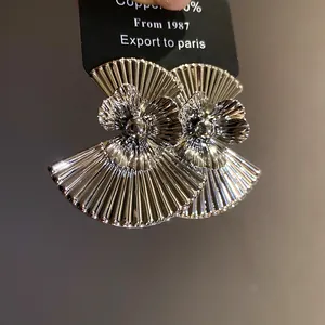 Detailed macro view of vintage metallic silver fan-shaped flower statement earrings