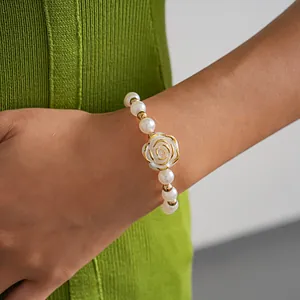 Detail of vintage camellia rose pearl bracelet worn on wrist with green knitwear