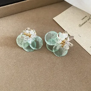 Detailed view of mint green floral drop earrings with clear petals and gold bead centers