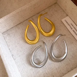 Detailansicht der quadratischen, gedrehten ovalen Creolen in mattem Gold- und Silber-Finish