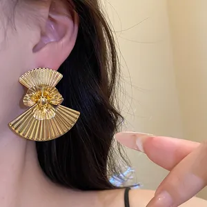 Close-up of vintage gold fan-shaped flower earrings with pleated metal texture details.