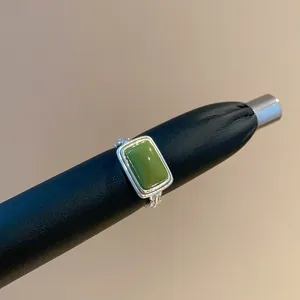 Detailansicht eines Vintage-Rings mit grünem Katzenaugenstein und geflochtenem Silberband