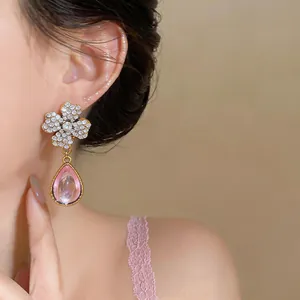 Elegante dettaglio di orecchini a fiore vintage con cristalli e resina rosa a goccia