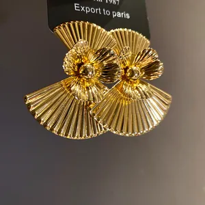 Detailed view of vintage gold-plated fan earrings with 3D pleated flower design.