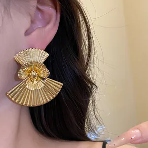 Detailed view of oversized vintage gold fan earrings with floral pleated metal design