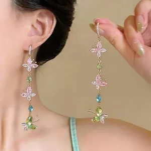 Close-up detail of elegant colorful butterfly zircon long tassel earrings on a model.