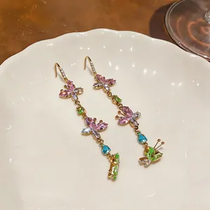 Close-up of colorful butterfly long tassel earrings with vibrant zircons on a white plate