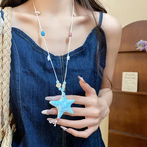 Primer plano de un collar de cuentas de estrella de mar azul llevado por una modelo.
