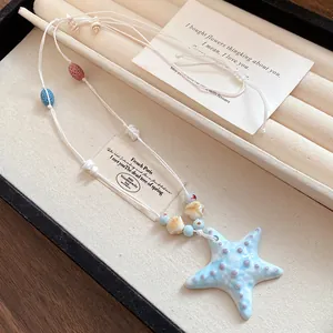 Vista detallada de un collar con colgante de estrella de mar azul claro en un joyero.