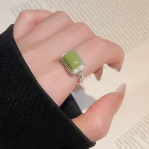 Nahaufnahme eines silbernen Vintage-Rings mit grünem Katzenaugen-Edelstein am Finger