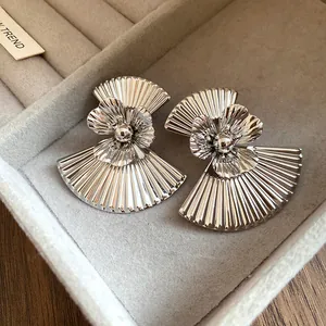 Detailed macro view of vintage silver fan-shaped metal earrings with pleated texture.