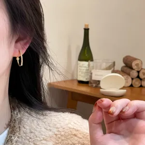 Close-up of elegant gold hoop earrings with sparkling brown zircons on model's ear