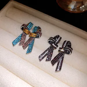 Primer plano detallado de aretes de nudo de cinta de diamantes en bandeja de terciopelo