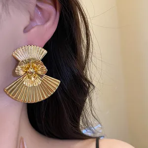 Detailed view of oversized vintage gold fan-shaped flower earrings on ear