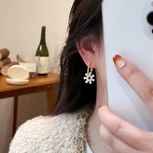 Detailed shot of a model wearing sweet gold flower zircon hoop earrings in mirror