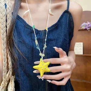 Detalle del colgante de estrella de mar amarilla en un collar de cuentas sobre una modelo