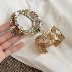 Detail view of a vintage multi-strand beaded bracelet and textured gold cuff set