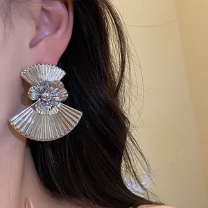 Detailed shot of a vintage silver fan-shaped earring with flower center on a model