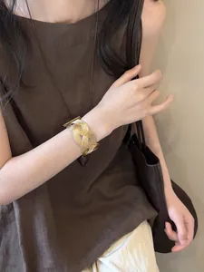 Detailed view of a Maillard vintage style gold-toned resin braided wide cuff bracelet worn on wrist