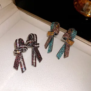 Primer plano de pendientes de nudo vintage con cristales de colores en su estuche