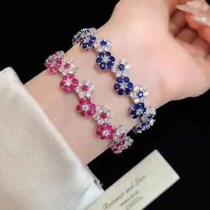 Close-up of sparkling zircon flower bracelets in pink and blue on a wrist