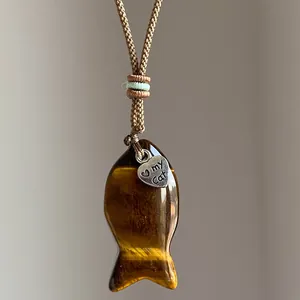 Nahaufnahme eines Fisch-Anhängers aus Tigerauge-Stein mit 'my Cat' Herz-Charm-Anhänger