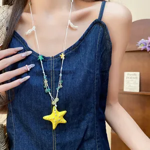 Detalle de primer plano de un collar de cuentas con estrella de mar sobre ropa vaquera