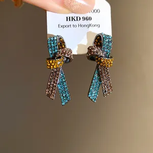 Vista detallada de pendientes de nudo vintage con cristales azules y amarillos