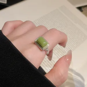 Makroansicht eines Vintage-Silberrings mit grünem Katzenaugenstein am Finger