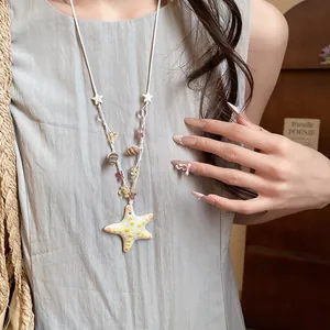 Primer plano de collar de cuentas de estrella de mar de colores con conchas playa.