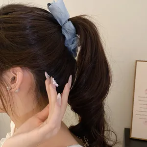 Detailed side view of blue ruffled fabric banana hair clip on high ponytail