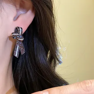 Detalle de cerca de un pendiente de nudo vintage con brillantes pedrería roja en la oreja.