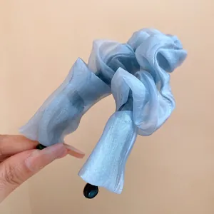 Macro detail of elegant light blue ruffled organza fabric banana clip for high ponytail styling