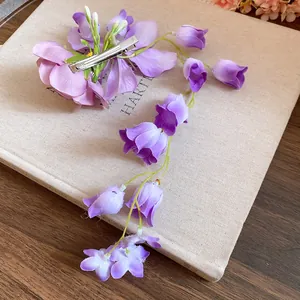 Close-up of a purple fabric flower hair clip with elegant long floral tassels
