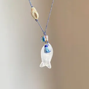 Detail der Vintage-Halskette mit fischförmigem Steinanhänger und blauem Quasten