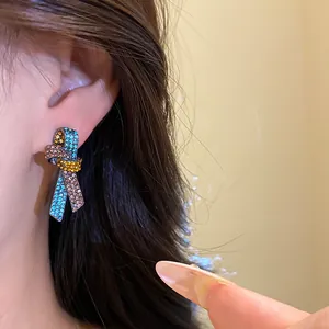 Primer plano de pendientes de nudo con pedrería de colores para un look vintage de lujo.