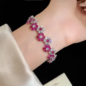 Detailed close-up showing the elegant flower-shaped bracelet with red and white sparkling zircons.