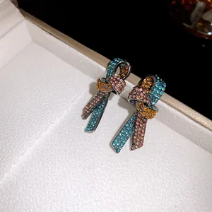 Primer plano de pendientes de nudo retro con diamantes de imitación de colores en caja.