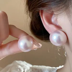 Detalle de pendientes de botón de perlas rosas irisadas de gran tamaño con agujas.