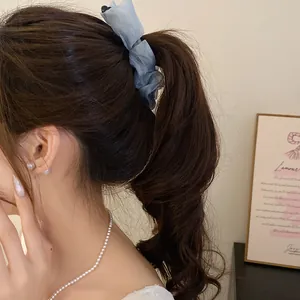 Close-up detail of a blue ruffled fabric banana hair clip holding a high ponytail