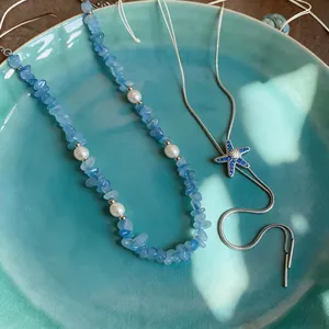 Close-up of blue beaded pearl necklace and starfish pendant necklace set in plate