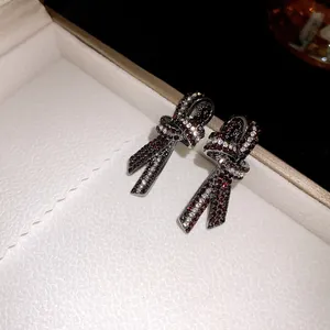 Detalle de pendientes de lazo vintage con brillantes diamantes de imitación rojos.