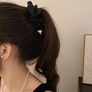 Close-up view of an elegant black pleated fabric banana clip for high ponytail styling