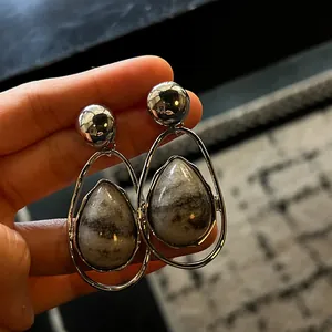 Close-up of vintage silver teardrop earrings with grey marbled stone inlay detail.